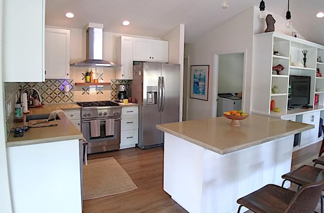 kitchen featuring tasteful backsplash, vaulted ceiling, sink, stainless steel appliances, and wall chimney exhaust hood