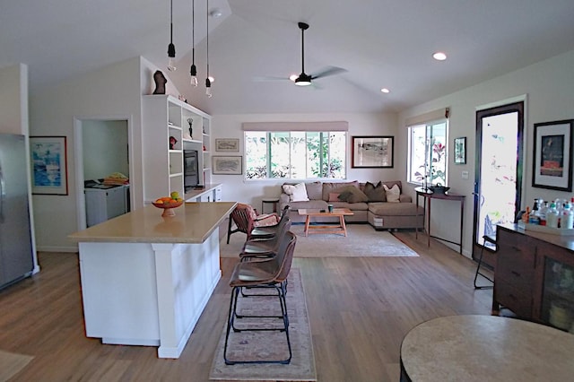 kitchen featuring a kitchen breakfast bar, pendant lighting, vaulted ceiling, and a kitchen island