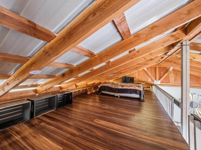 unfurnished bedroom with lofted ceiling with beams, dark wood-type flooring, and wood walls