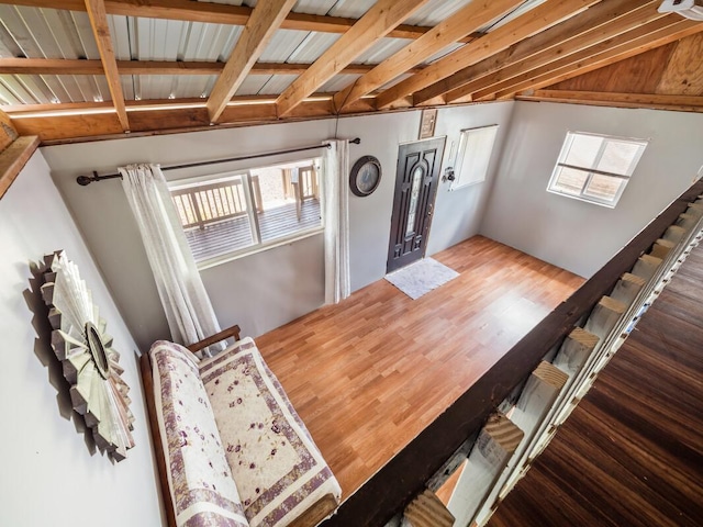 unfurnished dining area featuring lofted ceiling with beams and hardwood / wood-style flooring