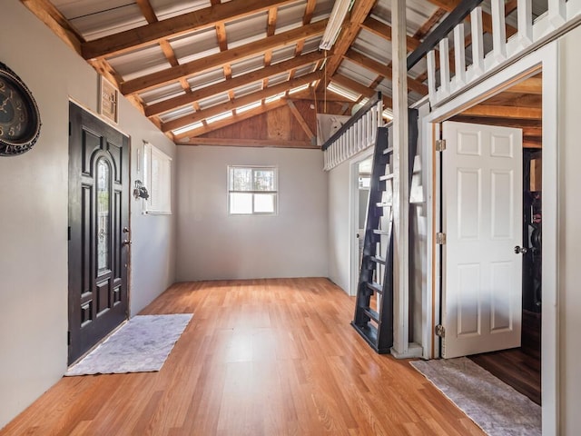 foyer with lofted ceiling with beams and light hardwood / wood-style floors