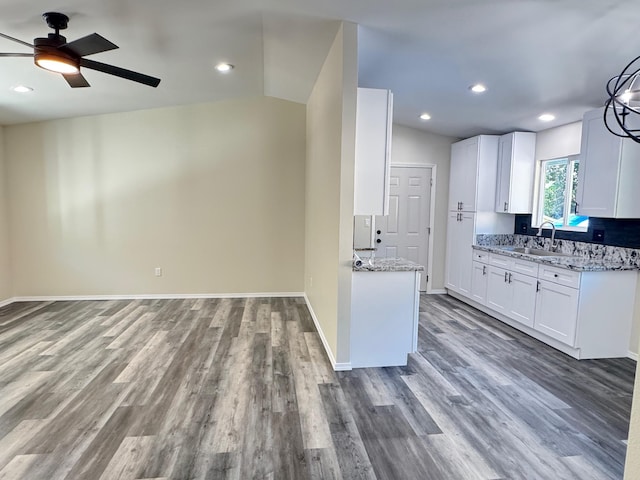 kitchen featuring white cabinets, vaulted ceiling, and light stone counters