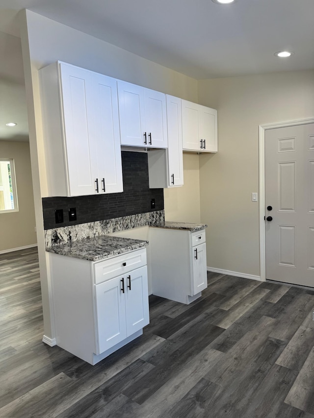 kitchen with white cabinets, dark hardwood / wood-style floors, tasteful backsplash, and dark stone countertops