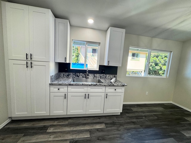 kitchen featuring light stone countertops, white cabinetry, and sink