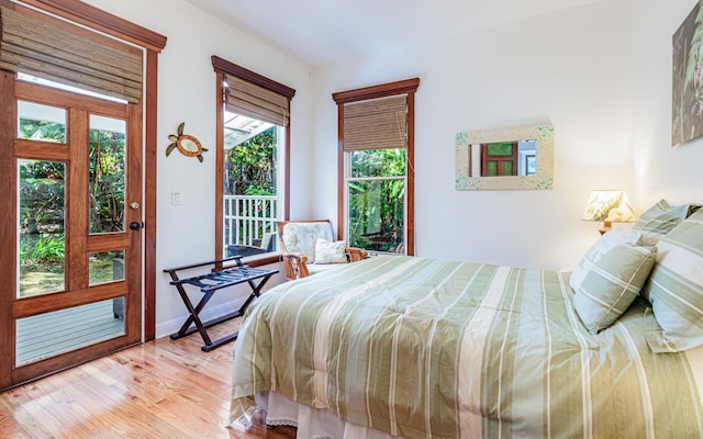 bedroom featuring multiple windows, access to outside, and light hardwood / wood-style floors