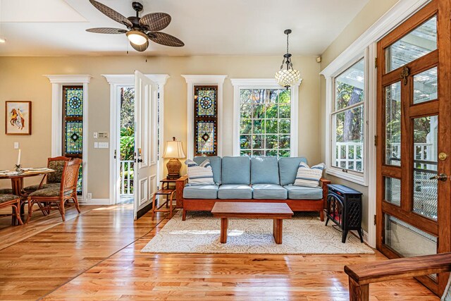 living room featuring ceiling fan with notable chandelier and light hardwood / wood-style floors