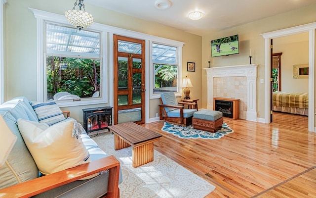 living room featuring a tile fireplace, wood-type flooring, and a wood stove