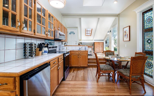 kitchen with stainless steel appliances, tile counters, decorative backsplash, and plenty of natural light