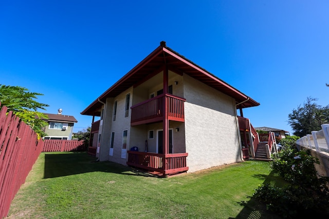 rear view of property with a balcony and a lawn