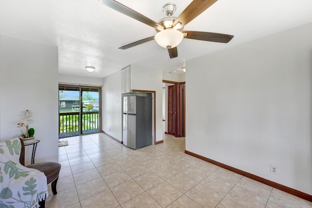 interior space featuring ceiling fan, stainless steel fridge, light tile patterned flooring, and white cabinetry