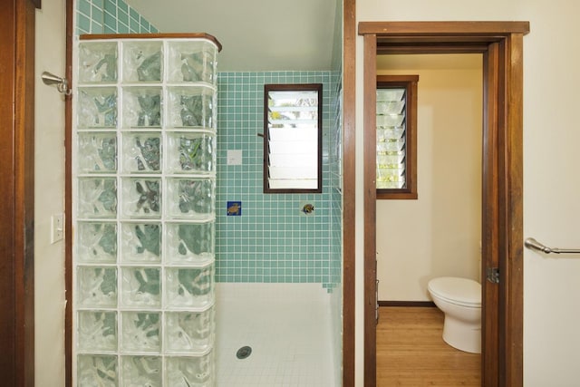 bathroom featuring toilet, a tile shower, and hardwood / wood-style flooring