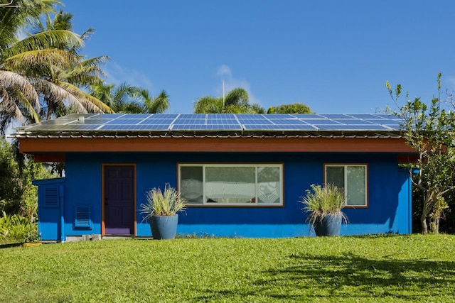 back of house featuring a yard and solar panels