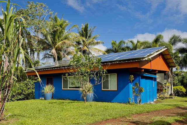 view of side of property featuring a lawn and solar panels