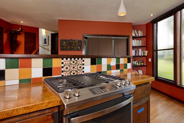 kitchen with light hardwood / wood-style floors, stainless steel range with gas cooktop, and backsplash