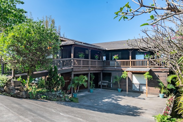 view of front facade with a wooden deck and a sunroom