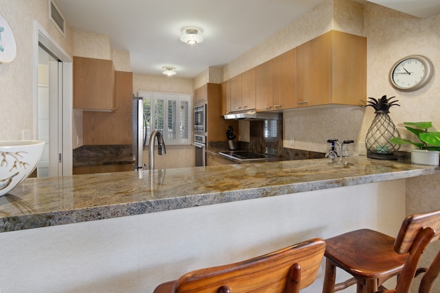 kitchen with sink, decorative backsplash, kitchen peninsula, and appliances with stainless steel finishes