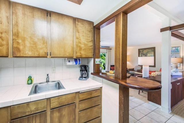 kitchen with tile counters, sink, light tile patterned flooring, and tasteful backsplash