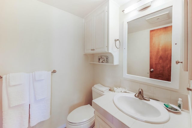 bathroom with toilet, backsplash, and vanity