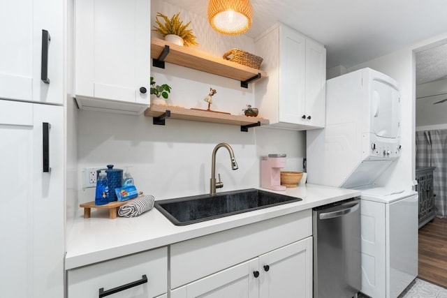 kitchen with sink, white cabinets, stainless steel dishwasher, and stacked washer / drying machine