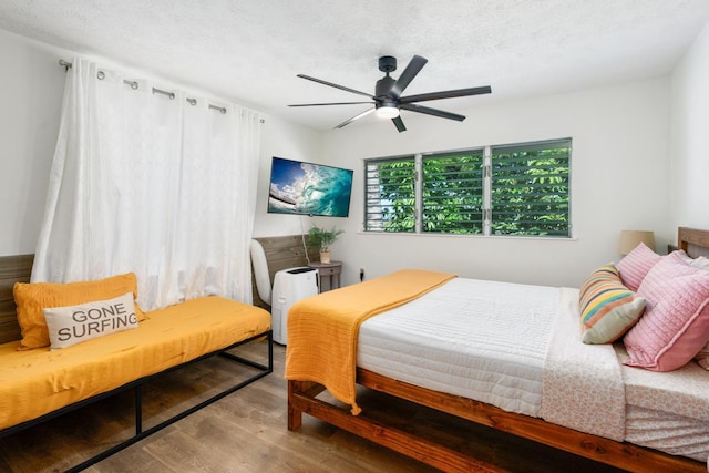 bedroom with hardwood / wood-style flooring, a textured ceiling, and ceiling fan