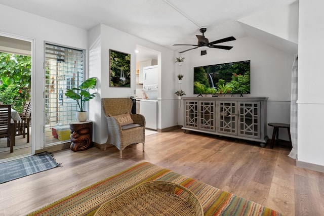 sitting room with stacked washer and clothes dryer, light wood-type flooring, and ceiling fan