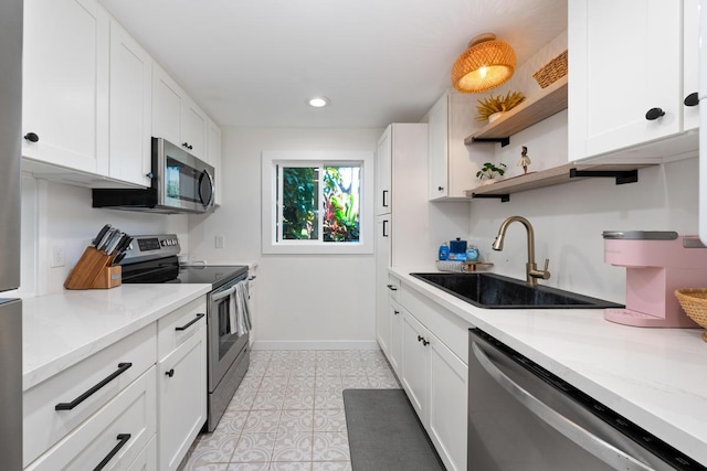 kitchen with sink, white cabinets, light stone counters, and appliances with stainless steel finishes