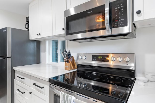 kitchen featuring light stone counters, appliances with stainless steel finishes, and white cabinetry