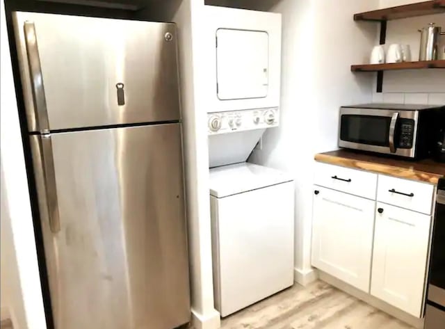 clothes washing area with stacked washer and dryer and light wood-type flooring