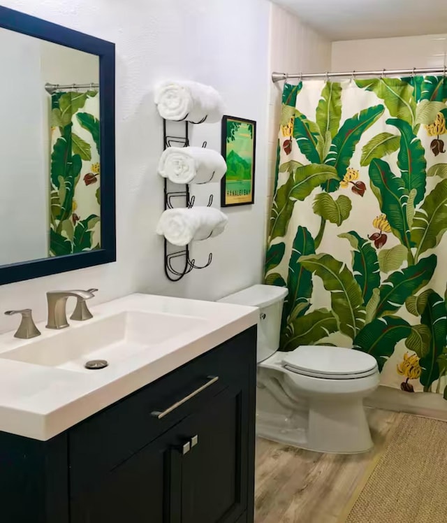 bathroom with toilet, vanity, and hardwood / wood-style flooring