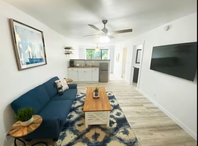 living room with ceiling fan, light hardwood / wood-style flooring, and sink