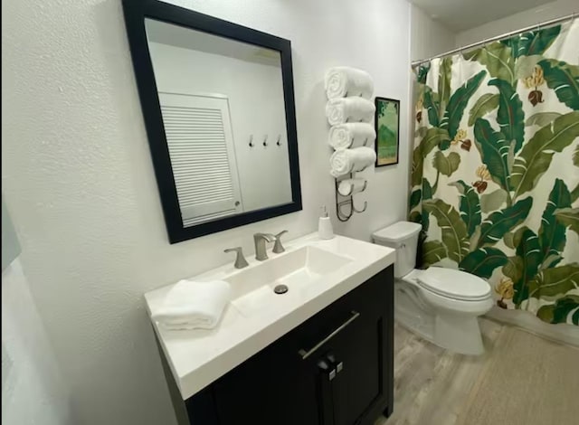 bathroom with toilet, walk in shower, wood-type flooring, and vanity