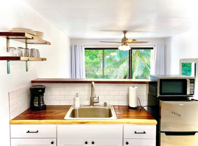 kitchen featuring butcher block countertops, decorative backsplash, and sink