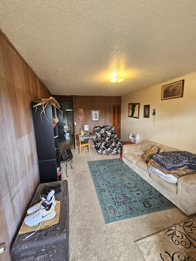 living room with carpet flooring, a textured ceiling, and wood walls