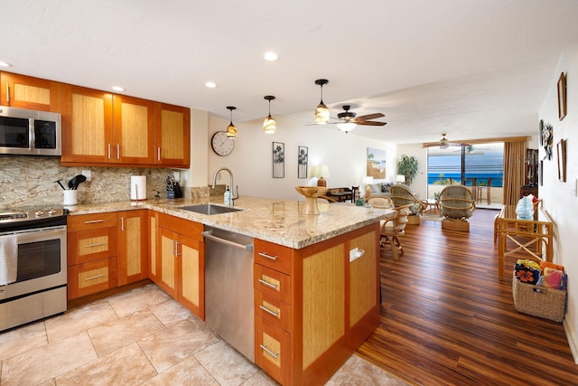 kitchen with tasteful backsplash, stainless steel appliances, kitchen peninsula, and sink