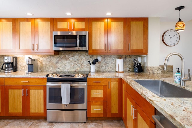 kitchen featuring sink, hanging light fixtures, stainless steel appliances, light stone countertops, and decorative backsplash