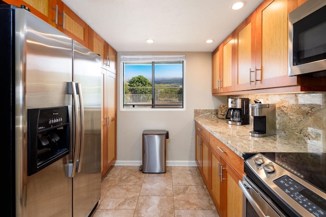 kitchen with light stone counters, stainless steel appliances, and light tile patterned flooring