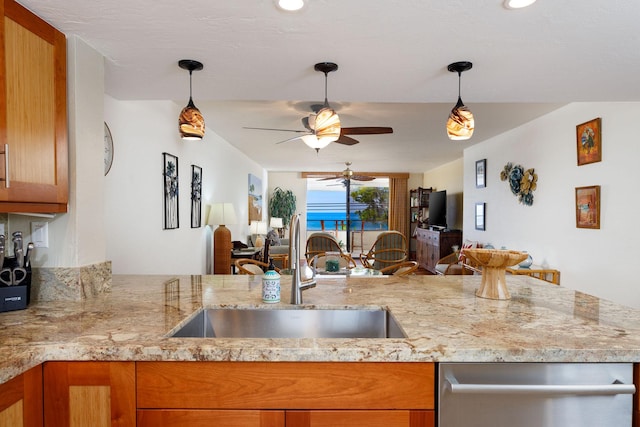 kitchen featuring sink, light stone counters, decorative light fixtures, stainless steel dishwasher, and kitchen peninsula