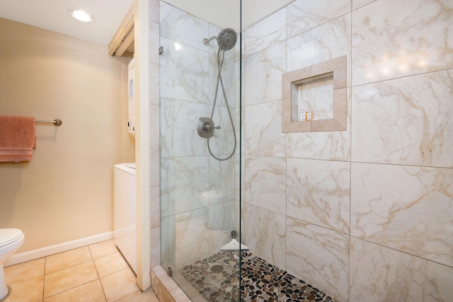 bathroom with stacked washer / dryer, tiled shower, tile patterned floors, and toilet