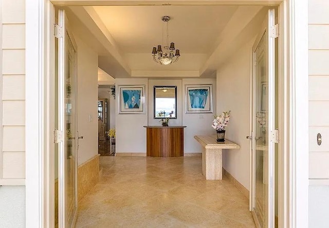 interior space featuring a raised ceiling and a notable chandelier