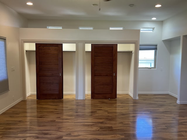 unfurnished bedroom with multiple closets, baseboards, dark wood-type flooring, and recessed lighting