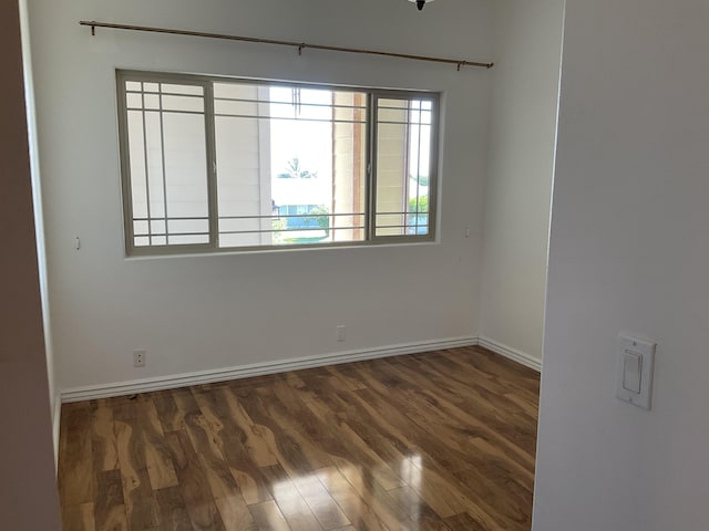 spare room with dark wood-style floors and baseboards