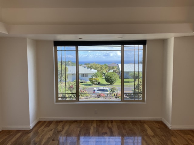 spare room with dark wood-style flooring and baseboards