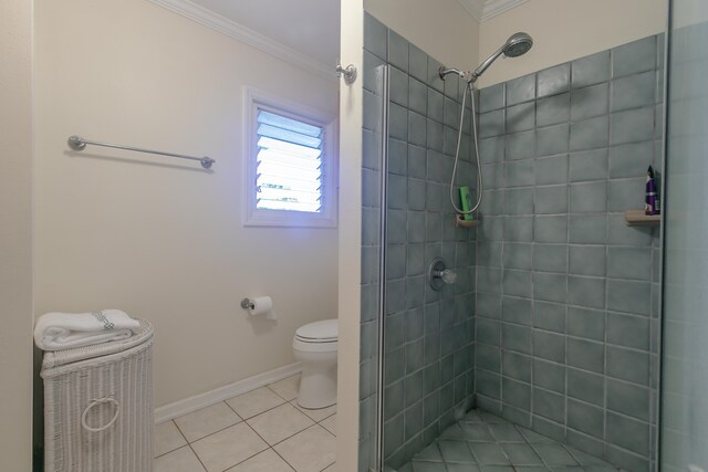 bathroom with tile patterned flooring, ornamental molding, toilet, and a tile shower