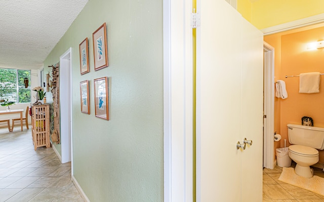 corridor with light tile patterned flooring and a textured ceiling