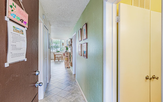 hall with light tile patterned floors and a textured ceiling