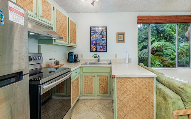 kitchen featuring appliances with stainless steel finishes, sink, light tile patterned floors, and a textured ceiling