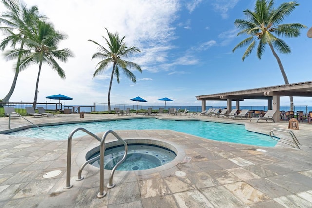 view of pool featuring a patio area, a hot tub, and a water view