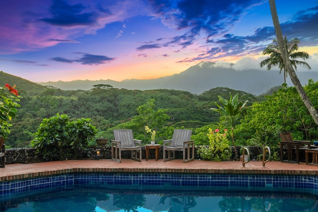 pool at dusk featuring a patio area and a mountain view