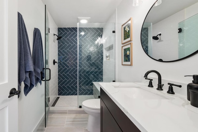 bathroom featuring vanity, a shower with shower door, and toilet