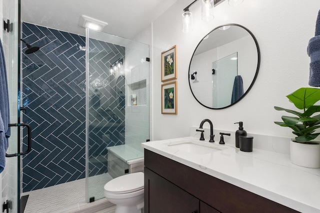 bathroom featuring vanity, a shower with door, and toilet